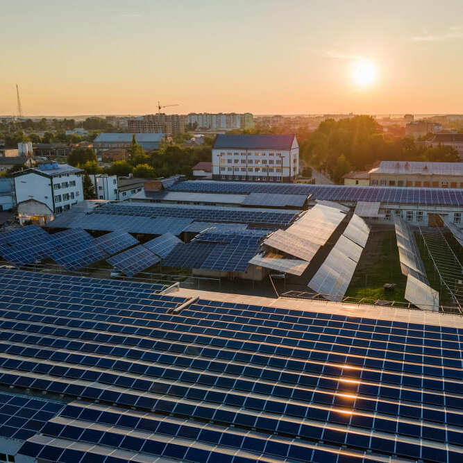 Vista aérea de una gran instalación de placas solares en una nave industrial al atardecer, representando el ahorro energético para empresas con Ojoalvatio.